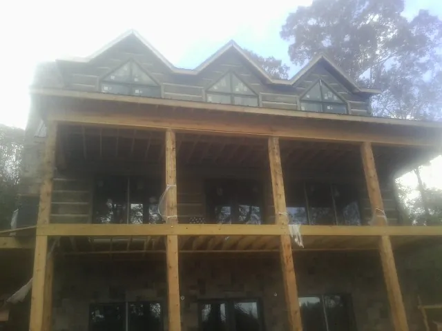 Dormers and porch framing on a large log home under construction — Roof Coating work by our crew in Calumet