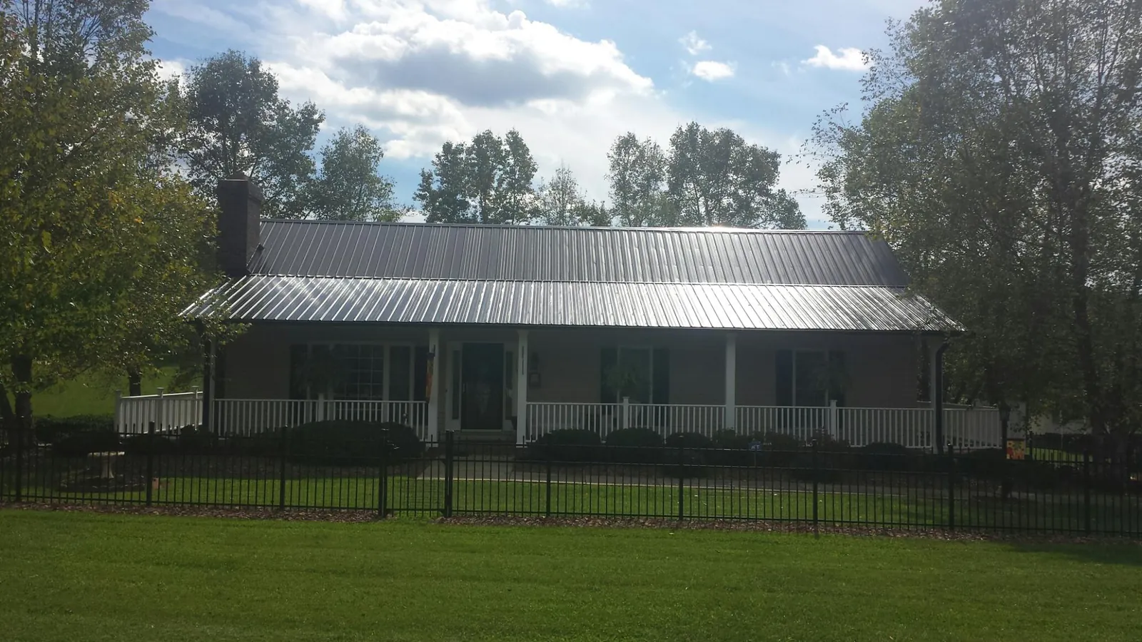 Gray metal roof on a brick ranch with a full width front porch — Gutter Guard Installation work by our crew in Calumet
