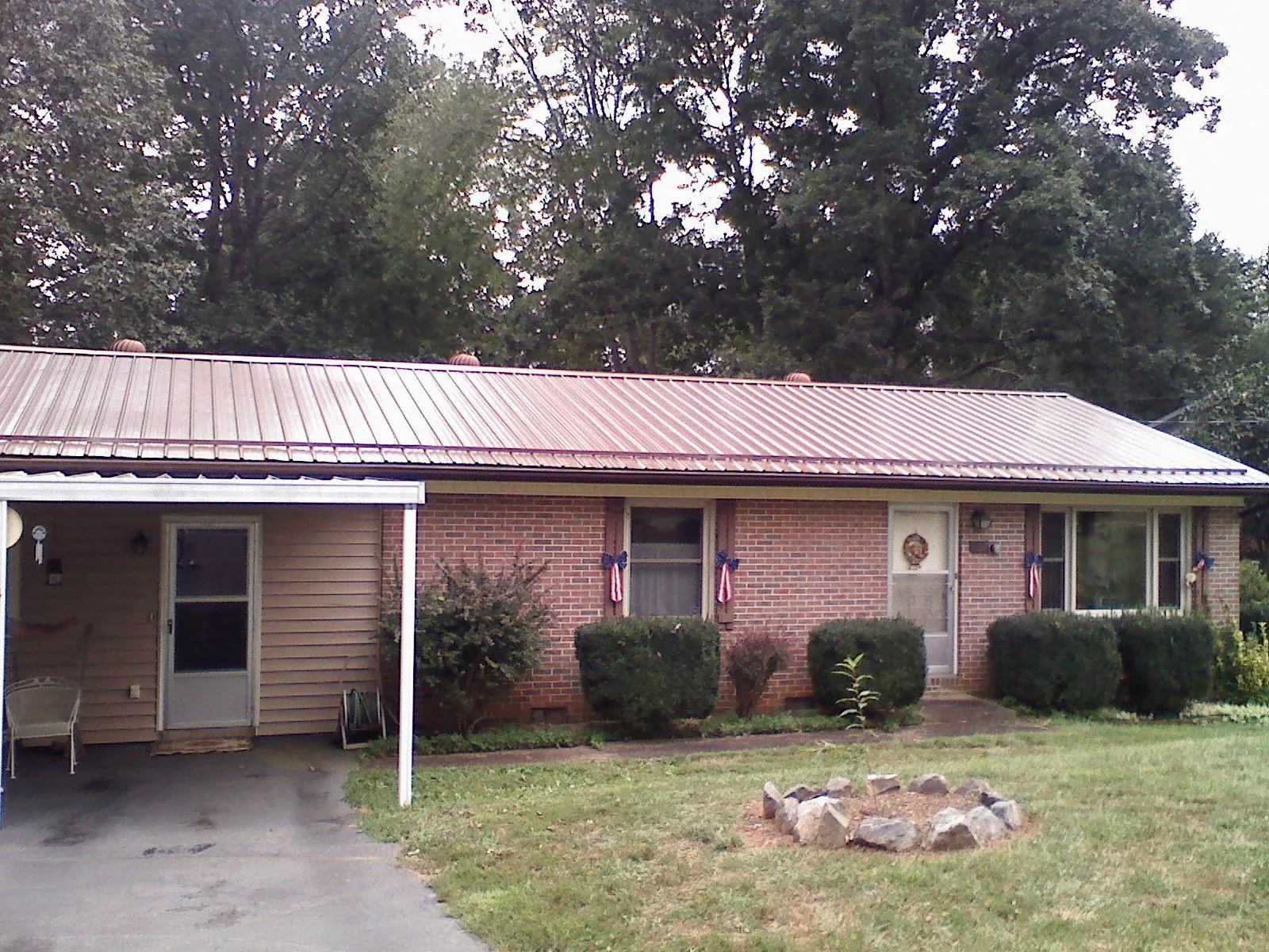 Bronze metal roof and carport on a brick ranch home — Roof Repair work by our crew in Calumet