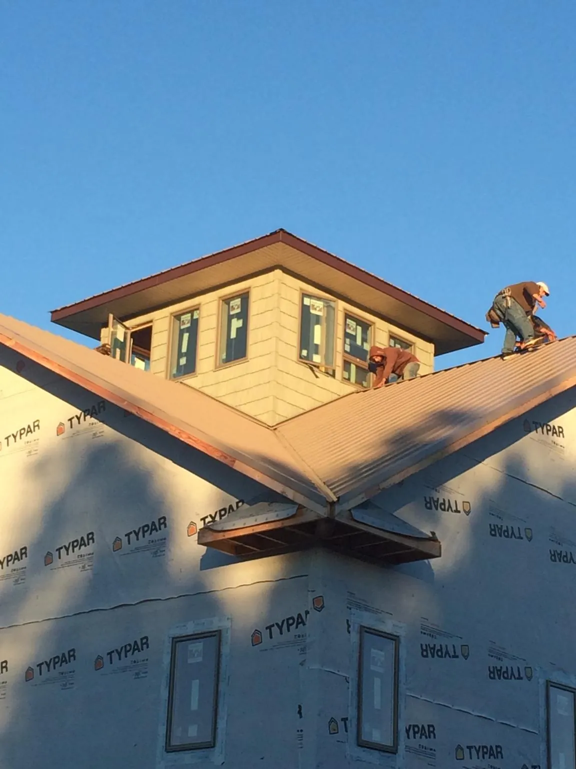 Roofers working around a rooftop cupola on a new metal roof at sunset — Roof Waterproofing in Calumet by Roofing Brothers